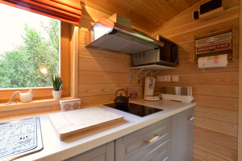Cocina luminosa y compacta del mobil home Manureva en Bélgica, con electrodomésticos modernos y paredes de madera.