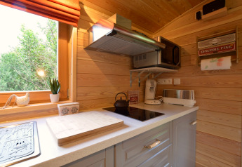 Cocina luminosa y compacta del mobil home Manureva en Bélgica, con electrodomésticos modernos y paredes de madera.