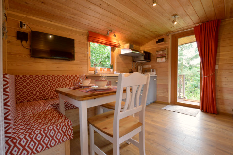 Acogedor interior de la casa móvil Manureva en Bélgica, con paredes de madera, comedor y cocina pequeña.
