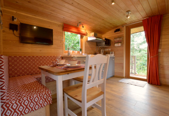 Acogedor interior de la casa móvil Manureva en Bélgica, con paredes de madera, comedor y cocina pequeña.