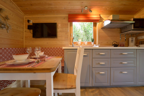 Interior de la casa móvil 'Manureva' en Bélgica con paredes de madera, mesa comedor y cocina moderna.
