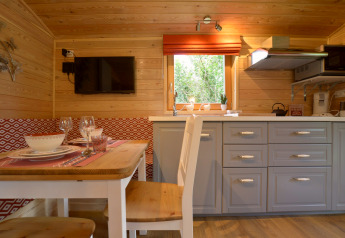 Interior de la casa móvil 'Manureva' en Bélgica con paredes de madera, mesa comedor y cocina moderna.