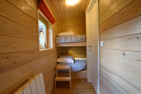 Dormitorio pequeño con literas y paredes de madera en la casa móvil Manureva en Bélgica.