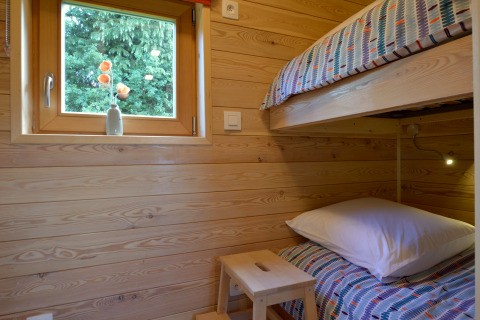 Dormitorio acogedor en la casa móvil Manureva en Bélgica con literas y pared de madera clara.