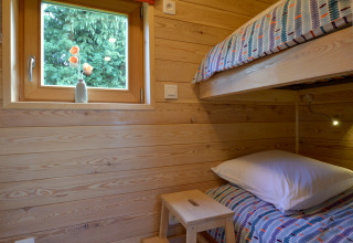 Dormitorio acogedor en la casa móvil Manureva en Bélgica con literas y pared de madera clara.