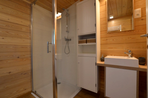 Baño con ducha, lavabo y paredes de madera en la casa móvil Manureva en Bélgica.