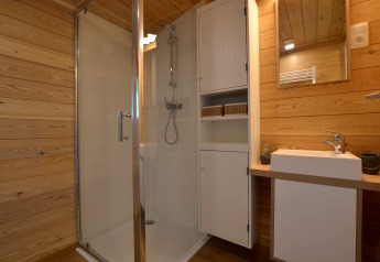 Baño con ducha, lavabo y paredes de madera en la casa móvil Manureva en Bélgica.