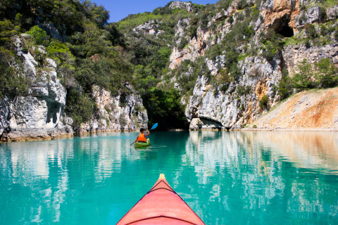 Personas en kayak navegan por aguas turquesas rodeadas de acantilados cerca de Artignosc-sur-Verdon, Francia.