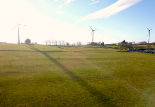 Vista de campos verdes con aerogeneradores cerca de la casa móvil Manureva en Bélgica en un día soleado.