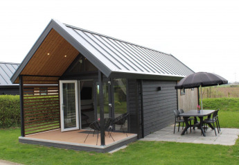 Sommer Lodge ved Rhederlaagse Meren, Holland, med åbent terrasseområde, bord, stole og parasol.