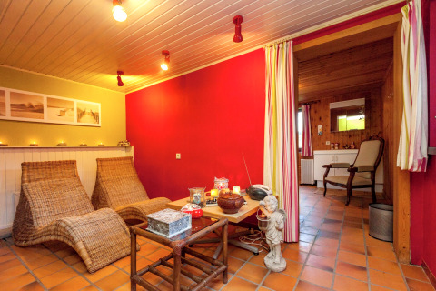 Acogedora zona de descanso en la casa móvil Manureva en Bélgica, con sillones de mimbre y velas.