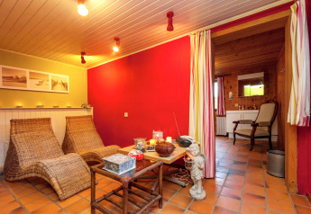 Acogedora zona de descanso en la casa móvil Manureva en Bélgica, con sillones de mimbre y velas.