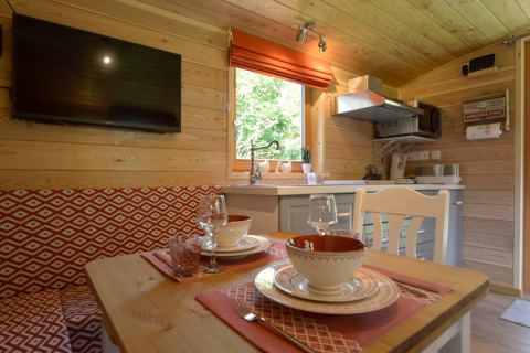Acogedora zona de comedor y cocina en la casa móvil Manureva en Bélgica, con paredes de madera y decoración moderna.