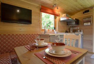 Acogedora zona de comedor y cocina en la casa móvil Manureva en Bélgica, con paredes de madera y decoración moderna.