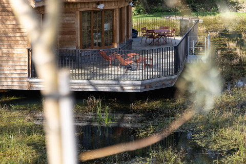 Cabaña 'The Funny Friends' en Bélgica, con terraza sobre el agua y zona de descanso al aire libre.