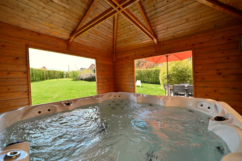 Jacuzzi intérieur dans un chalet en bois, vue sur jardin et terrasse au lodge Ard Zen en Belgique.