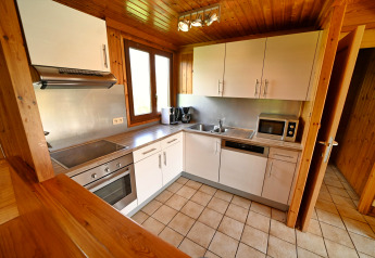 Moderne lodgekeuken met witte kasten, oven, magnetron en houten afwerking in Ard Zen, België.