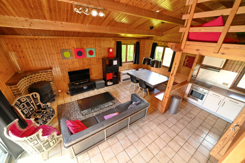 Salon chaleureux du lodge Ard Zen en Belgique avec canapé, coin repas moderne et murs en bois.