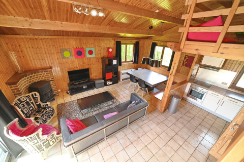 Cozy living area at Ard Zen lodge in Belgium, featuring modern design, sofa, dining area, and wood walls.