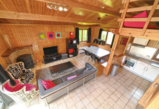 Cozy living area at Ard Zen lodge in Belgium, featuring modern design, sofa, dining area, and wood walls.