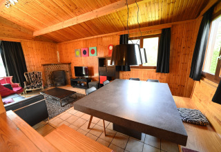 Living room with wood paneling, modern furniture, and large windows at Ard Zen lodge in Belgium.