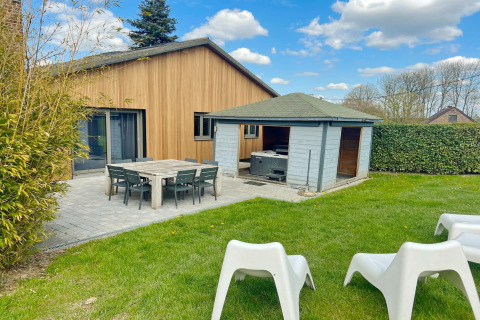 Photo of Ard Zen lodge in Belgium with wood exterior, patio dining, garden shed, and green lawn.