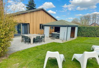 Photo of Ard Zen lodge in Belgium with wood exterior, patio dining, garden shed, and green lawn.