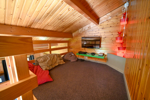 Mezzanine chaleureuse en bois, coussins, TV et éclairage dans le lodge Ard Zen en Belgique.