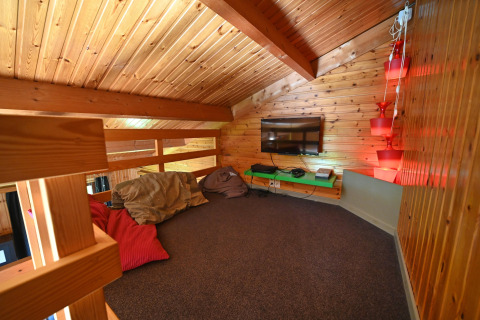 Cozy loft lounge with wooden walls, bean bags, a TV and lighting at Ard Zen lodge in Belgium.