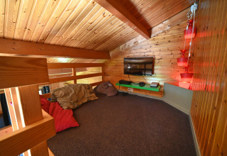 Cozy loft lounge with wooden walls, bean bags, a TV and lighting at Ard Zen lodge in Belgium.