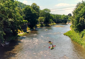 Kajakkers varen op een rivier omringd door bomen nabij Ard Zen Lodge in België.