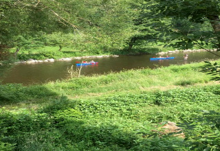 Vue sur une rivière près du lodge Ard Zen en Belgique, avec des personnes en canoë et verdure.
