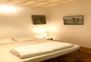 Slaapkamer in Les Peupliers de la Pecherie lodge in België met tweepersoonsbed, kussens en wanddecoratie.