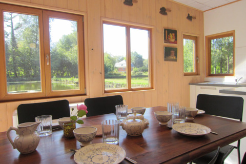 Lichte eetruimte bij lodge Les Peupliers de la pecherie in België met tafel en uitzicht op vijver en natuur.