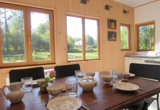 Lichte eetruimte bij lodge Les Peupliers de la pecherie in België met tafel en uitzicht op vijver en natuur.