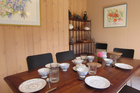 Eetkamer bij Les Peupliers de la pecherie, België met gedekte tafel, servies, glazen en bloemen op tafel.