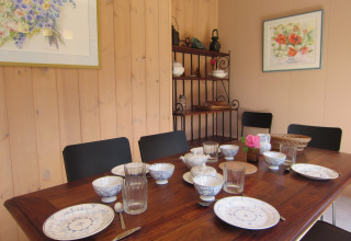 Eetkamer bij Les Peupliers de la pecherie, België met gedekte tafel, servies, glazen en bloemen op tafel.
