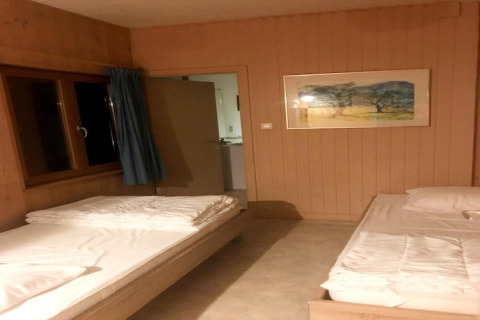 Eenvoudige lodgekamer in Les Peupliers de la pecherie in België, met twee bedden en open deur.