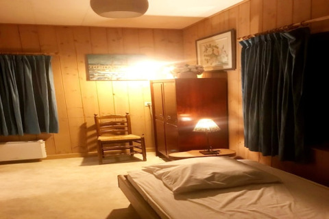Een knusse slaapkamer bij Les Peupliers de la Pecherie in België met houten wanden en blauwe gordijnen.