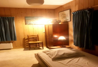 Een knusse slaapkamer bij Les Peupliers de la Pecherie in België met houten wanden en blauwe gordijnen.
