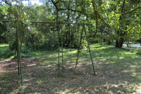 Schommel in het gras bij Les Peupliers de la pecherie lodge, omringd door bomen en natuur in België.