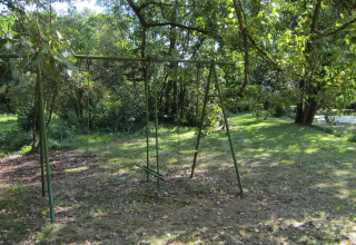 Schommel in het gras bij Les Peupliers de la pecherie lodge, omringd door bomen en natuur in België.