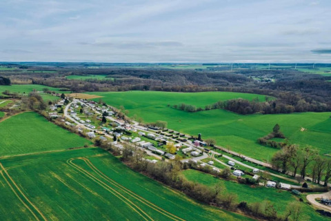 Luchtfoto van Les Peupliers de la Pecherie-lodge in België, omringd door groene velden en bosgebieden.