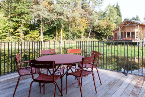 Terraza exterior con mesa y sillas en Cabane The Funny Friends, Bélgica, vista al bosque y la cabaña.