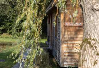Houten lodge 'The Funny Friends' in België, omgeven door groen en een rustige omgeving.