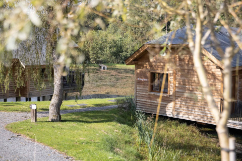 Træhytter ved søen med natur omkring, Cabane 'The Funny Friends' lodge i Belgien, solrig dag.