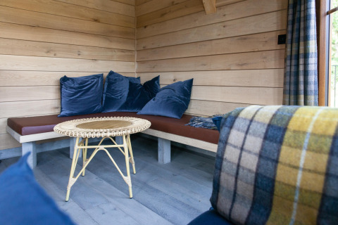 Acogedor rincón en la cabaña 'The Funny Friends' en Bélgica, con paredes de madera y cojines azules.