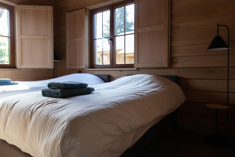 Dormitorio en Cabane The Funny Friends, Bélgica, con camas individuales, paredes de madera y luz natural.