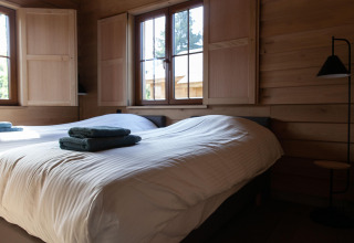 Dormitorio en Cabane The Funny Friends, Bélgica, con camas individuales, paredes de madera y luz natural.