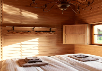Camera da letto in legno illuminata, lodge 'Happiness', Belgio, letto matrimoniale, asciugamani e finestra.